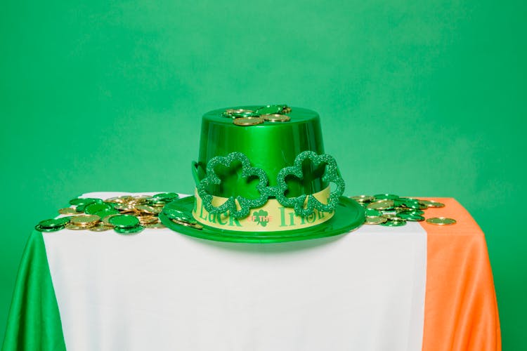 Green Hat And Coins On Table With Irish Flag