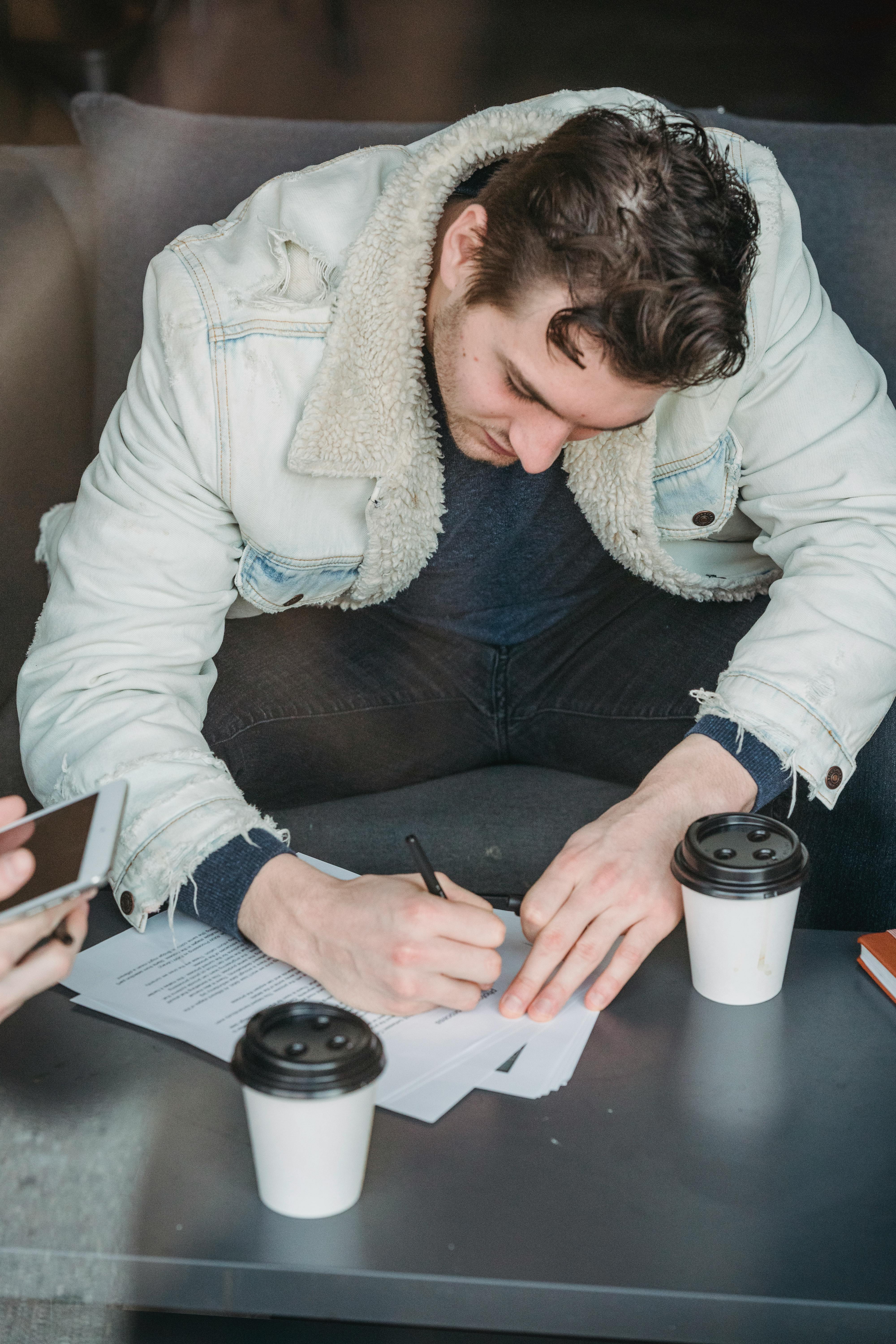Young man signing documents in cafe