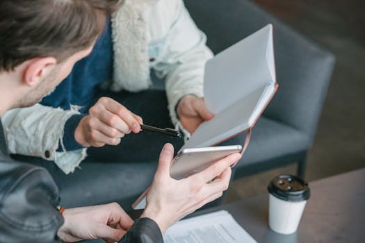 Two adults in a casual business meeting, discussing notes and digital device.