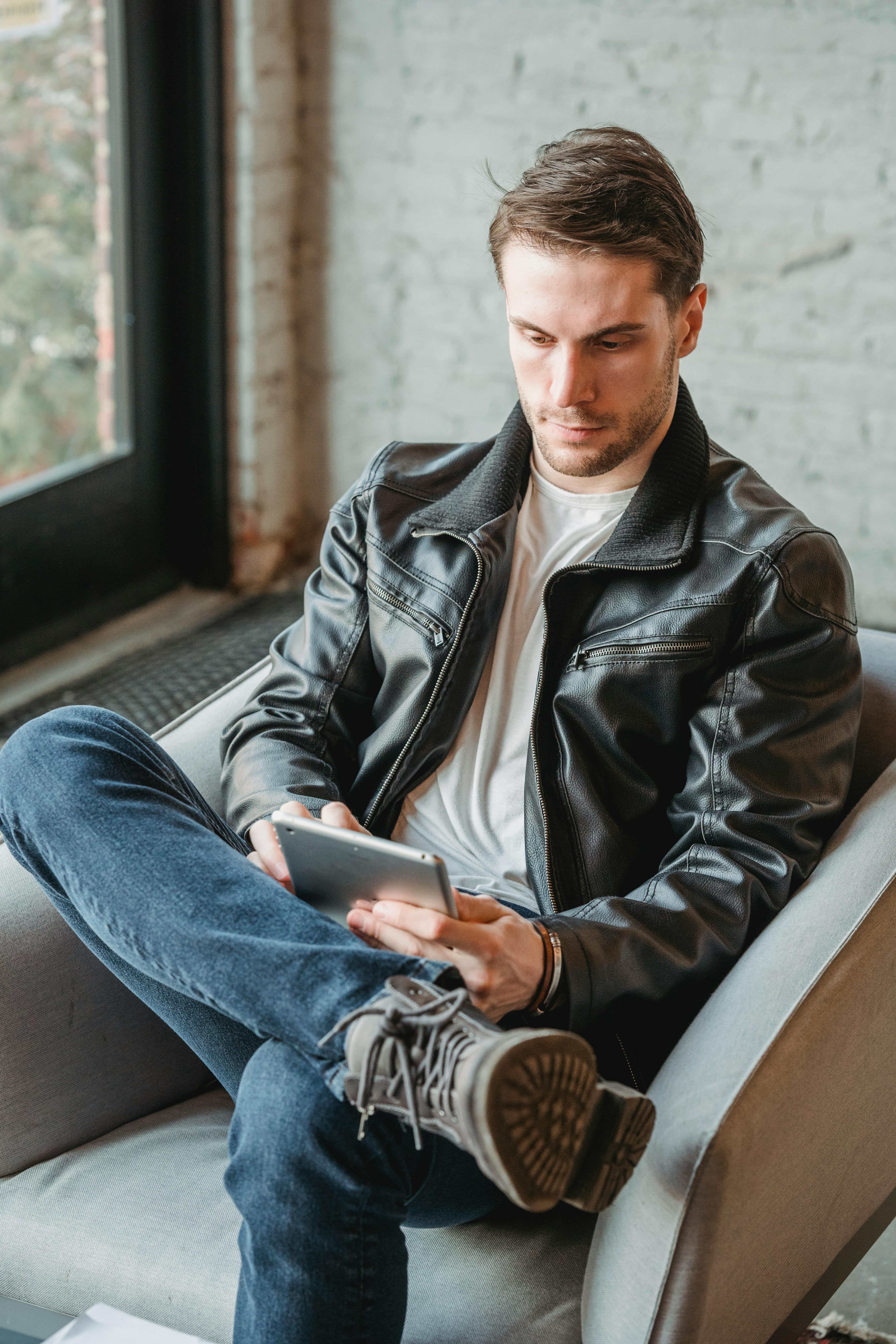 serious man using tablet while sitting in armchair