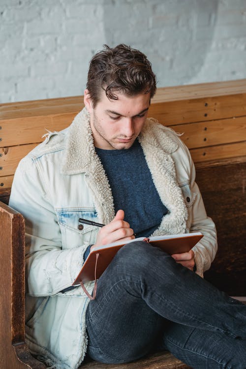 Serious man writing notes while sitting on bench