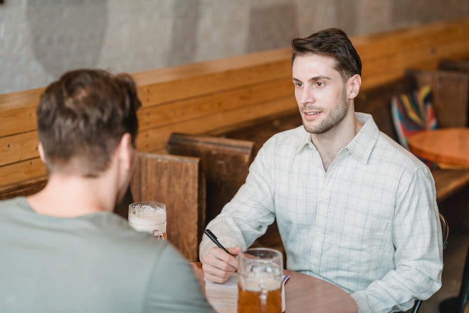 Business partners talking while signing agreement at table with beer