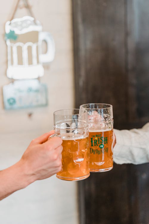 Free Crop unrecognizable men gathering together and drinking tasty beer on blurred background in bar Stock Photo