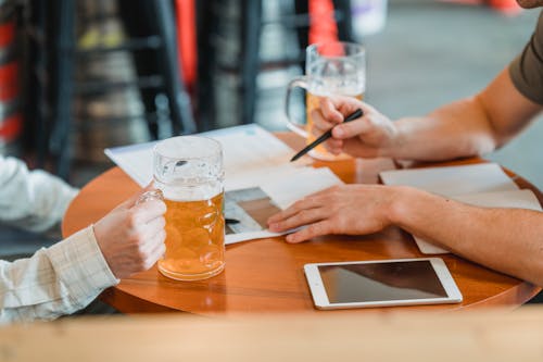 Businessmen discussing contract on paper at table with beer