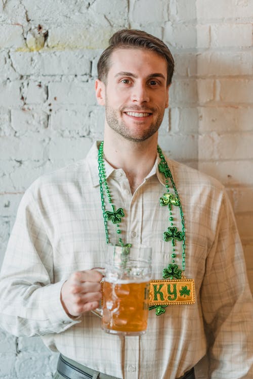 Positive bearded male in causal shirt and St Patricks day decorations smiling and looking at camera