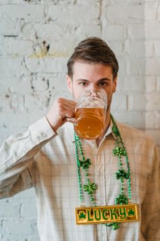 Bearded male with dark hair and glass of beer celebrating traditional St Patricks day while looking at camera
