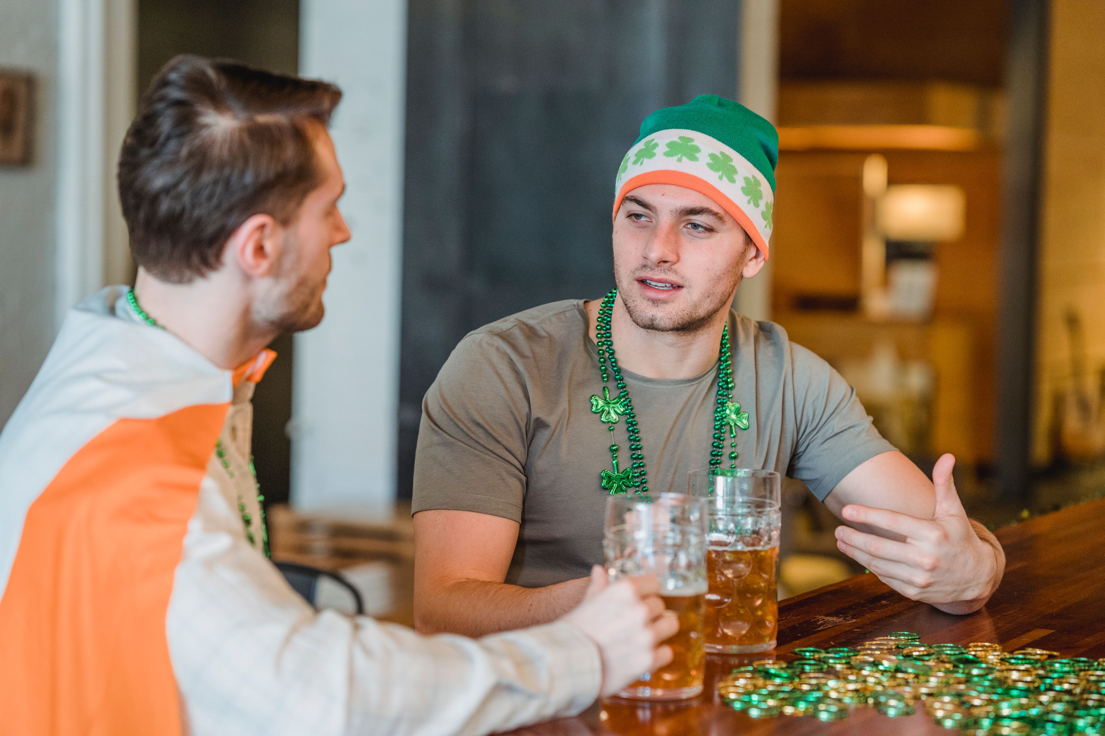 Two men enjoying drinks and conversation at a bar on Saint Patrick's Day.