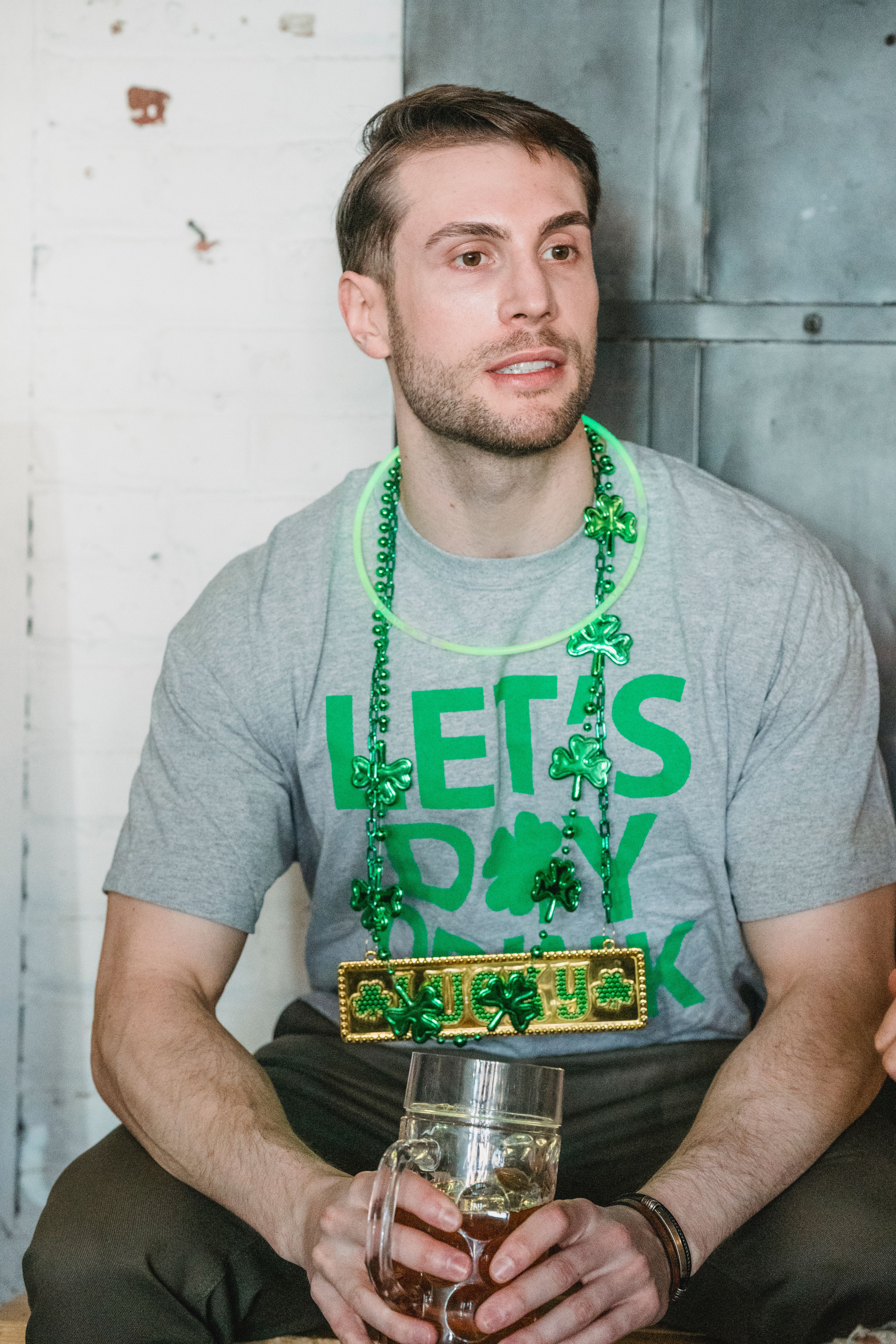 Caucasian man celebrating St. Patrick's Day with festive green attire and beer.
