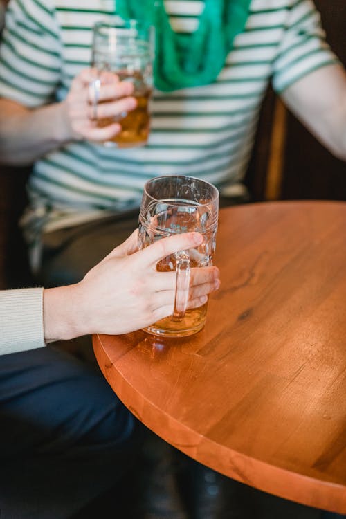 Faceless friends with beer interacting in pub