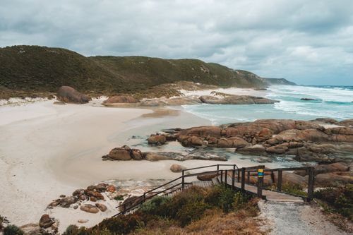 Free Amazing scenery on wide sandy Lights Beach with rocky formations and grassy hill washing by foamy ocean against cloudy sky in Albany Stock Photo