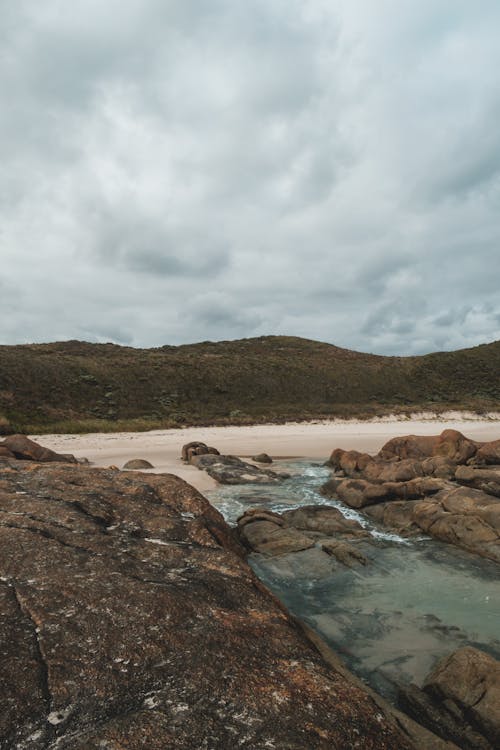 Overcast sky over sandy seacoast with rocky formations