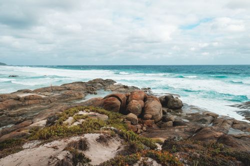 Free Picturesque view of rough coast washed by foamy turquoise sea under cloudy sky in peaceful nature Stock Photo
