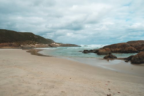 Sandy beach and stiff cliffs washed by azure sea