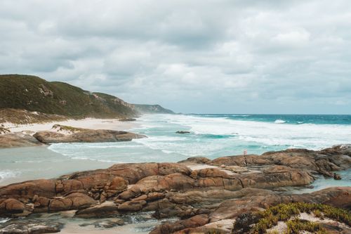 Free Picturesque view of rocky uneven seacoast washed by turquoise foamy sea waves beneath cloudy gloomy sky Stock Photo