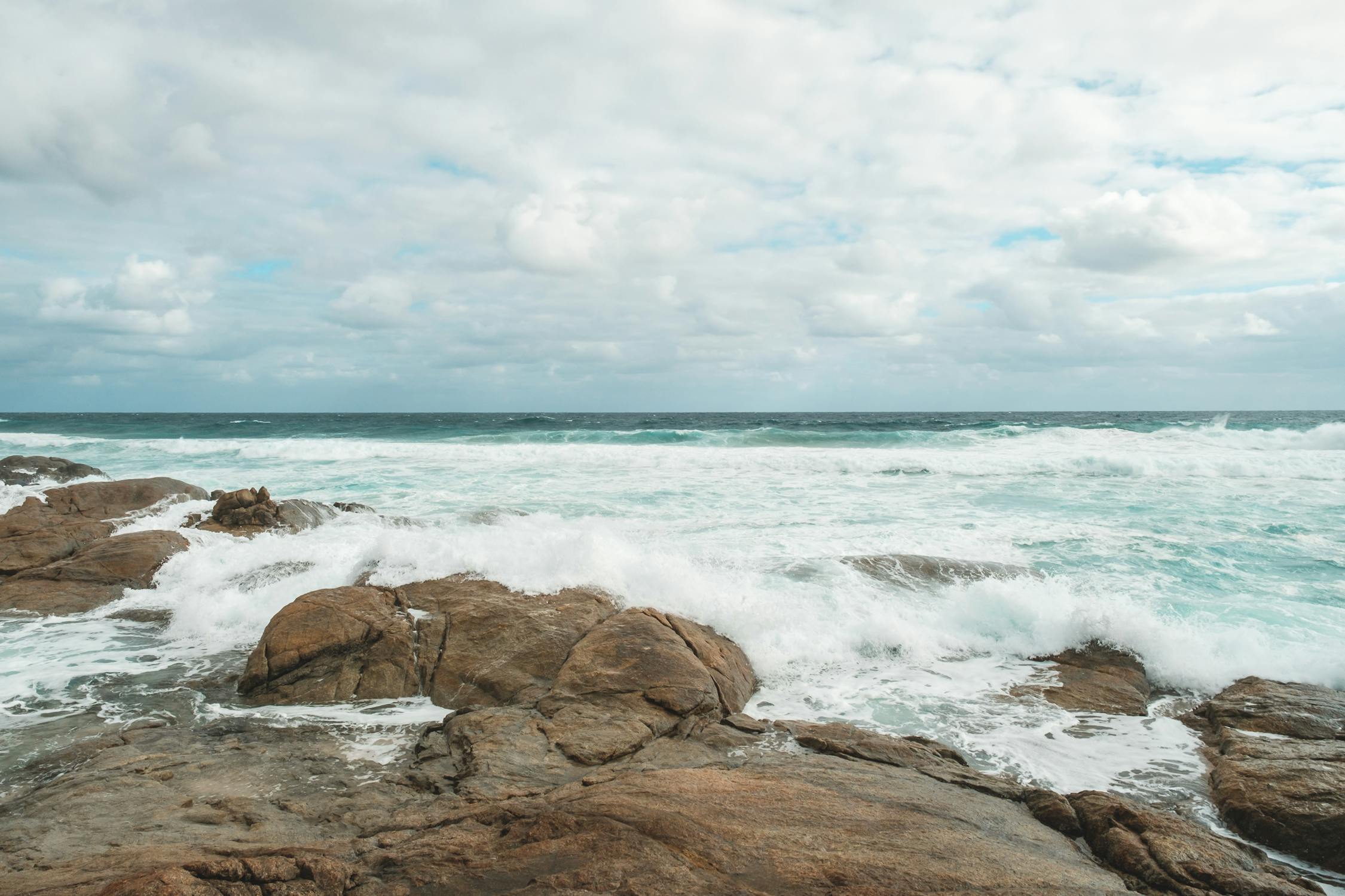 Rocky seacoast washed by foamy blue sea · Free Stock Photo