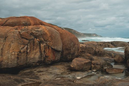 Free Rough rocky seashore with massive stones near stormy azure sea waving under gloomy cloudy sky Stock Photo