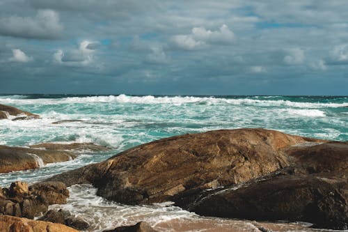 Free Picturesque azure sea waves rolling on rough stony coast Stock Photo