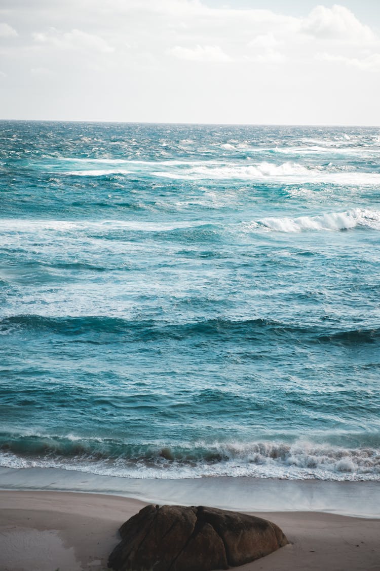 Foamy Waves Washing Sandy Beach With Big Stone