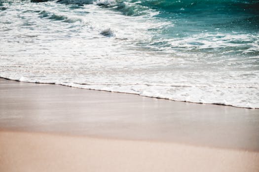 Peaceful sandy beach with gentle ocean waves and soft sunlight, perfect for a tranquil getaway.