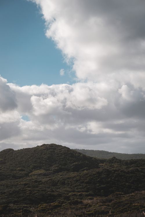 Free Scenic landscape of mountain range covered with lush green forest against cloudy blue sky on sunny day Stock Photo