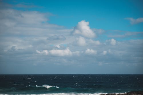 Free Endless wavy ocean meeting cloudy blue sky Stock Photo
