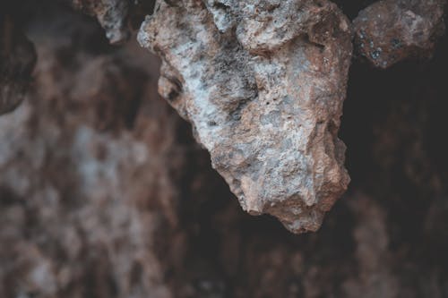 Heavy textured piece of stone on uneven formation on rocky cave in daytime