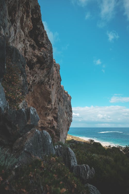 Heavy rocky cliff on coast washed by foamy ocean