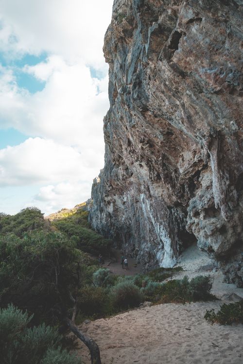 Free Majestic rough stony cliff surrounded with verdant plant under tranquil cloudy sky in daylight Stock Photo