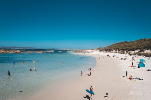 Free Many people relaxing on sandy beach of tranquil ocean under cloudless bright blue sky Stock Photo