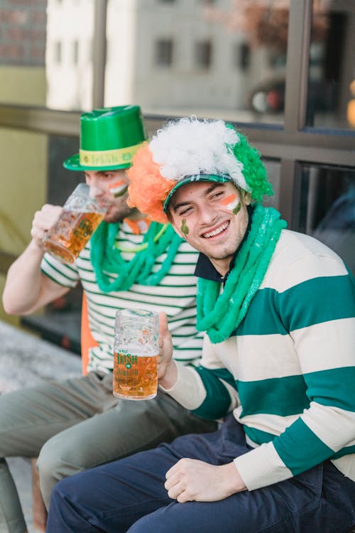 Content young guys drinking beer while celebrating St Patricks Day on street