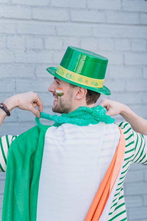 Free Back view of positive male in colorful traditional outfit standing near wall during Saint Patricks day on street in city Stock Photo