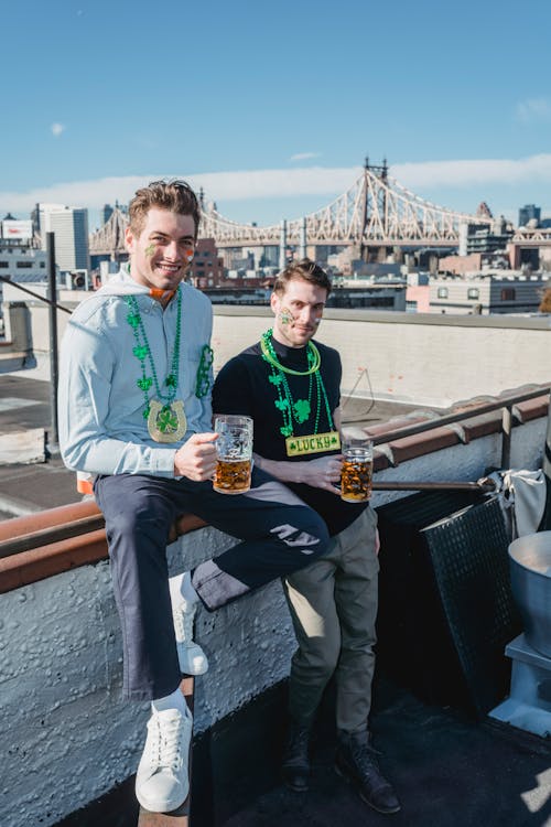 Cheerful millennials drinking beer while celebrating St Patricks Day in city