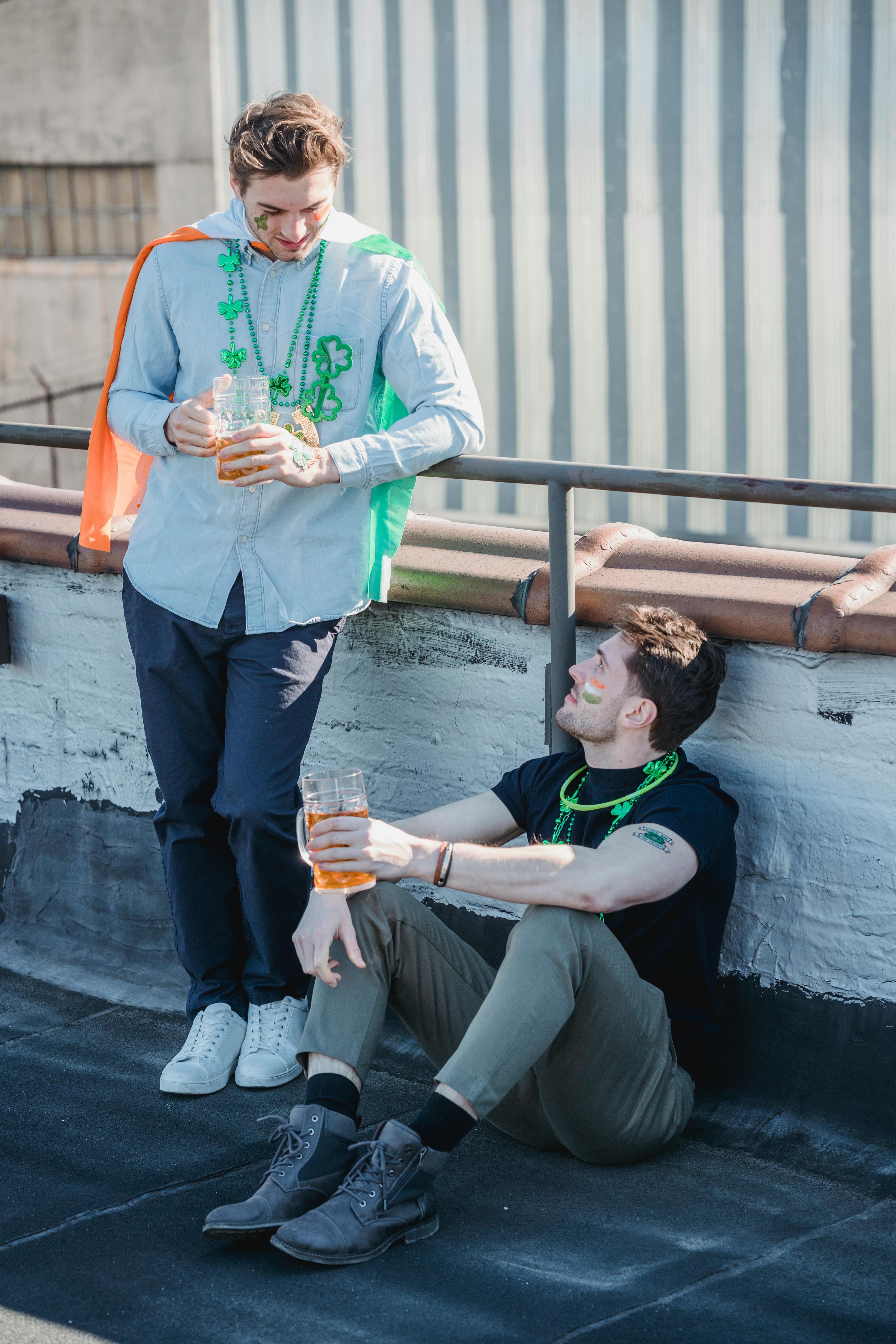 young male friends boozing beer on roof and communicating