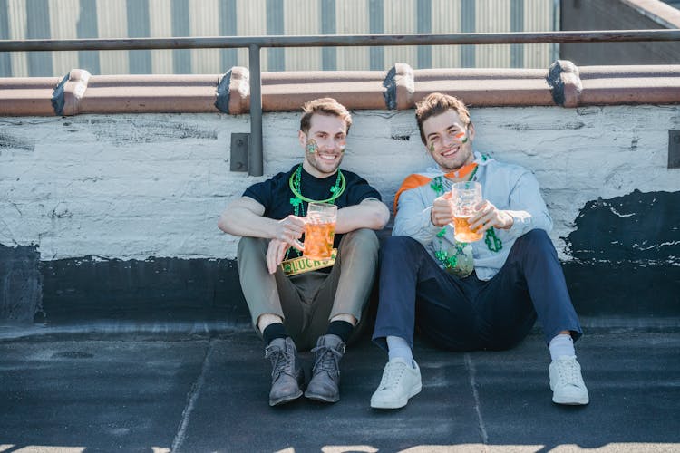 Happy Young Guys Chilling On Roof With Beer While Celebrating St Patricks Day