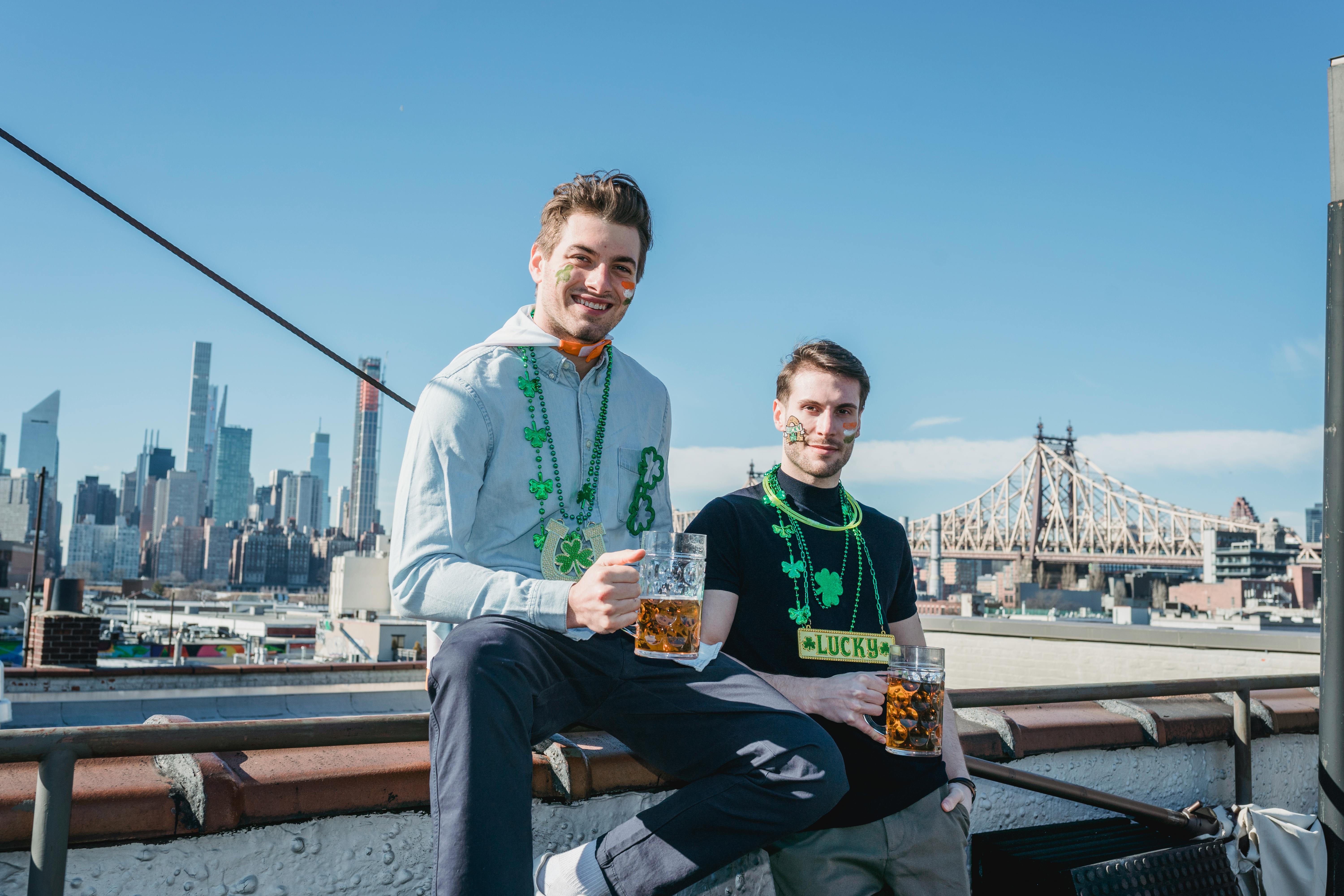 content guys drinking beer on roof with picturesque city view