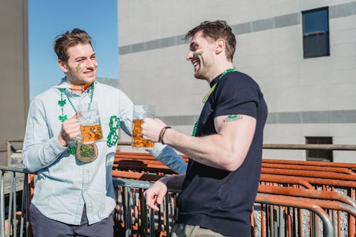 Delighted young male best friends boozing beer and celebrating Irish feast