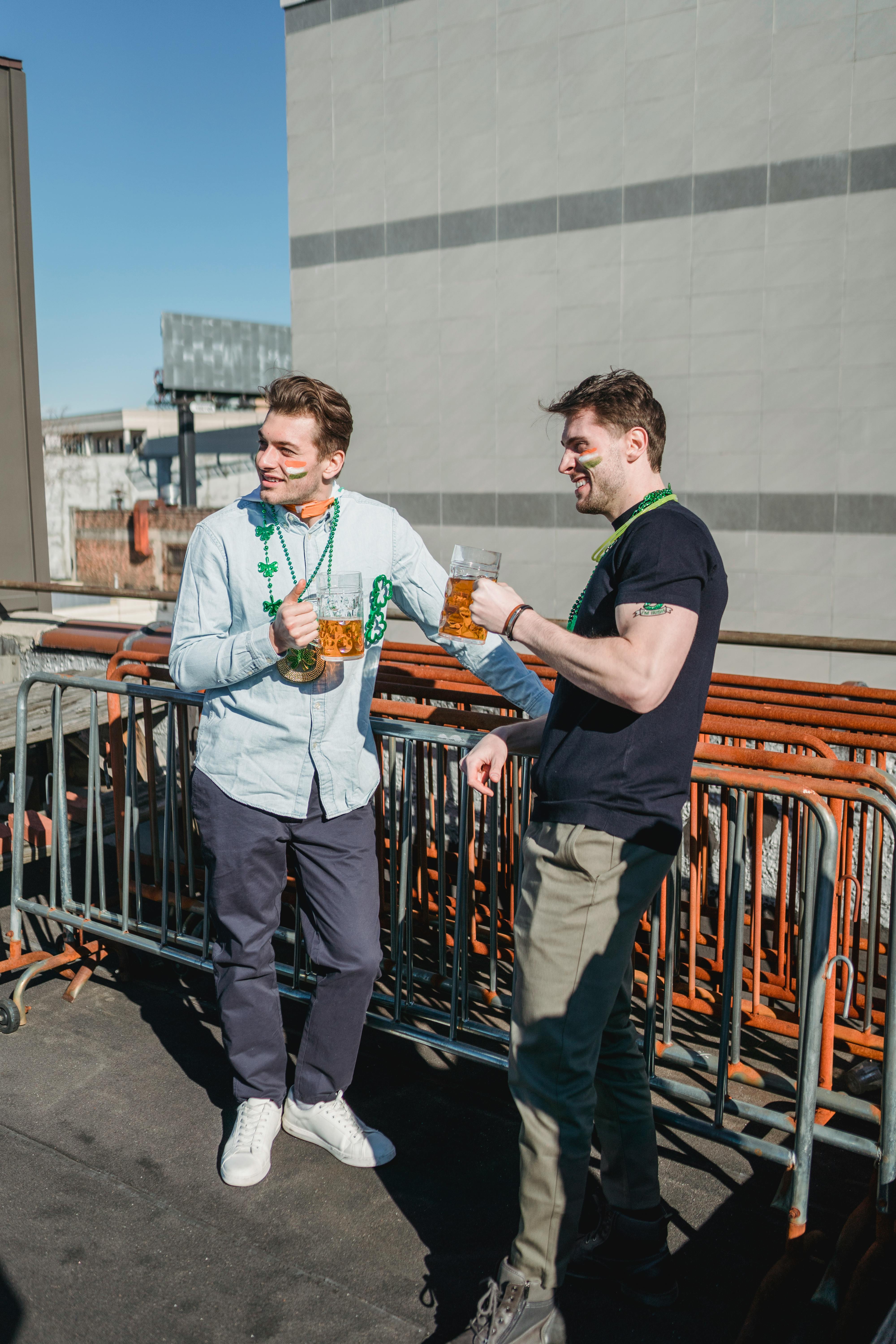 joyful guys drinking refreshing beer on veranda on sunny day