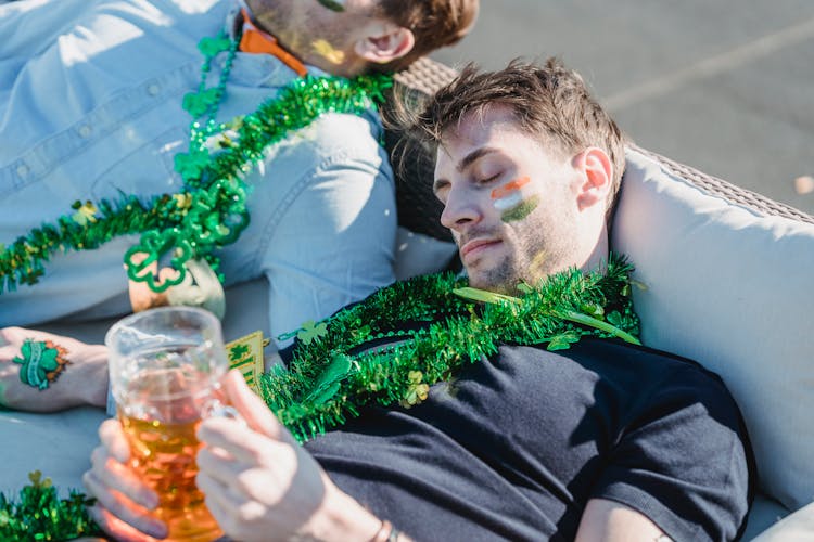 Drunk Man With Painted Irish Flag On Face Sleeping On Sofa After Party