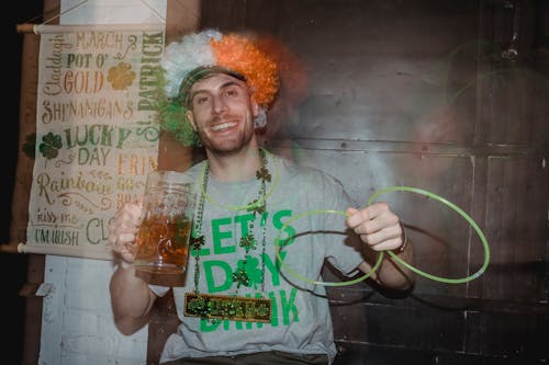 Laughing guy in clown wig and with neon glow stick necklace on party