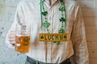 Crop man carrying glass of beer in national necklace with shamrock symbols