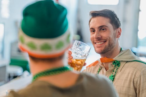 Cheerful man drinking beer and talking with friend