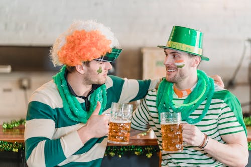 Positive friends hugging and drinking beer at St Patricks Day