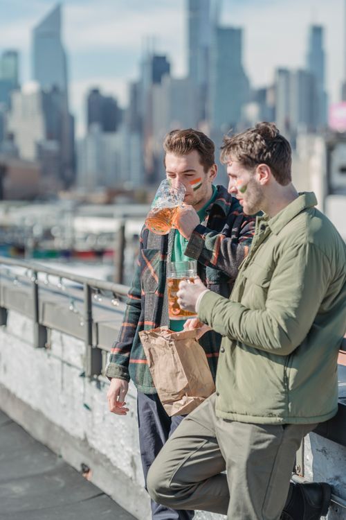 Free Fans of national team wearing warm clothes with national flag colors on cheeks drinking beer and eating fast food and staying in the street of modern city Stock Photo