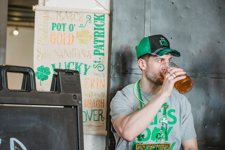 Young Man Drinking Beer In Bar On St Patricks Day