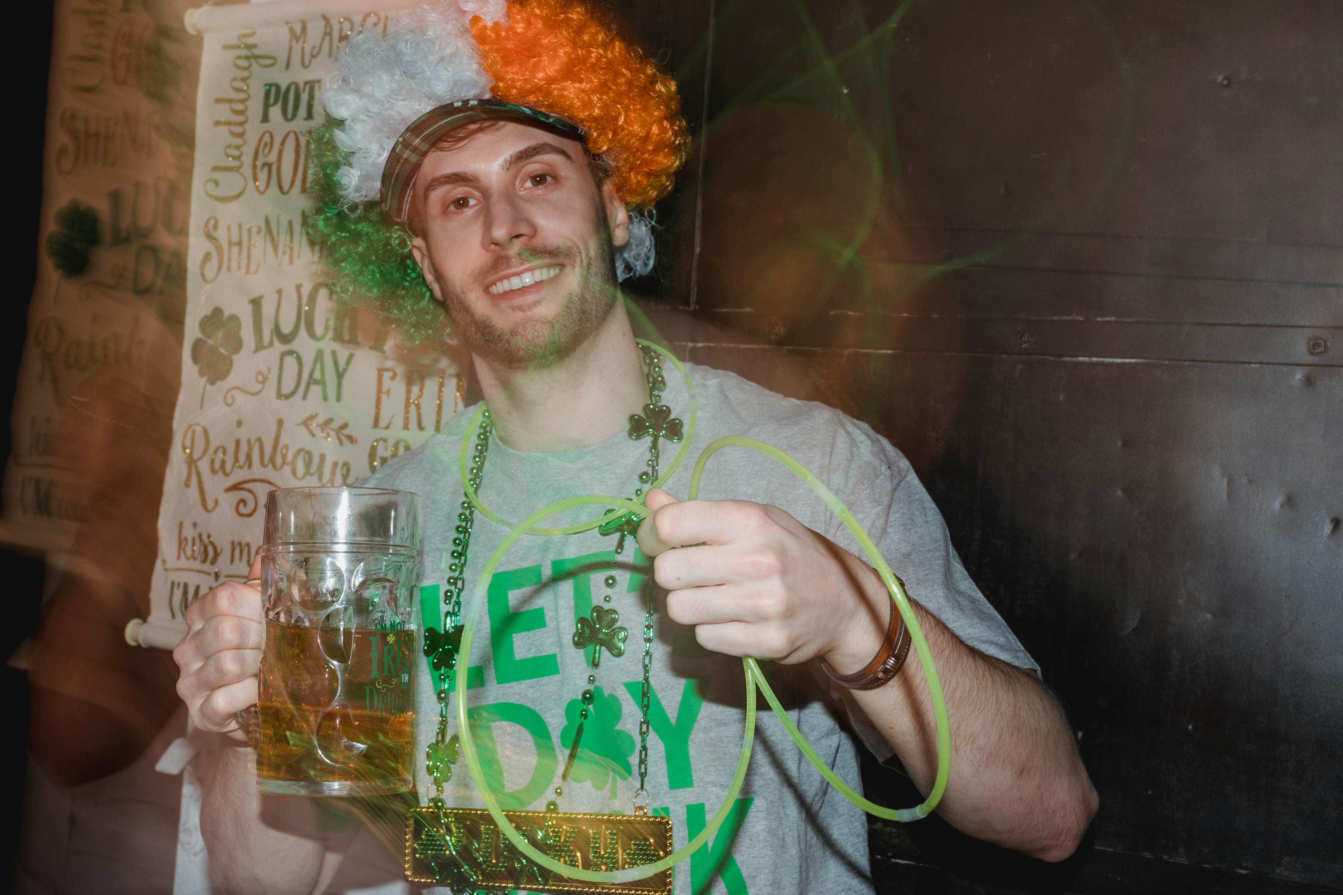 joyful young guy with beer glass celebrating st patricks day in pub