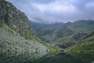 宁静的山地景观中，平静的湖泊映衬着薄雾弥漫的天空