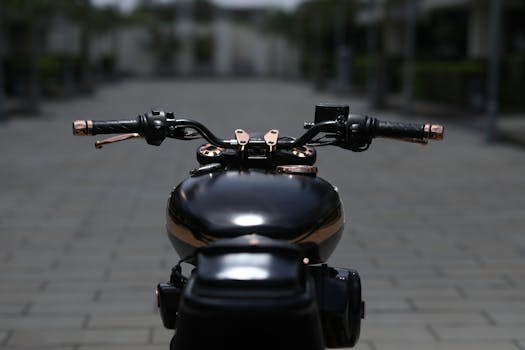 Black motorcycle handlebars in focus, highlighting detail and craftsmanship.