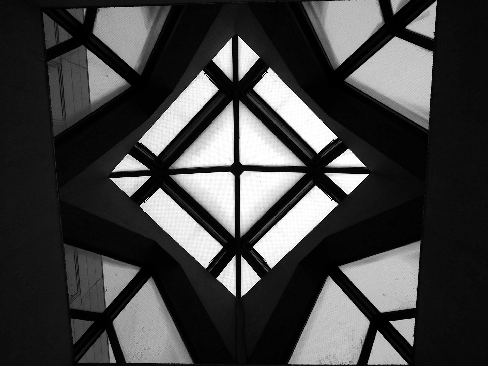 From below black and white of glass ceiling with rhombus shaped ornament in contemporary building in daylight