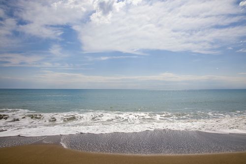 Free Tranquil seaside view with gentle waves under a bright blue sky, perfect for relaxation. Stock Photo