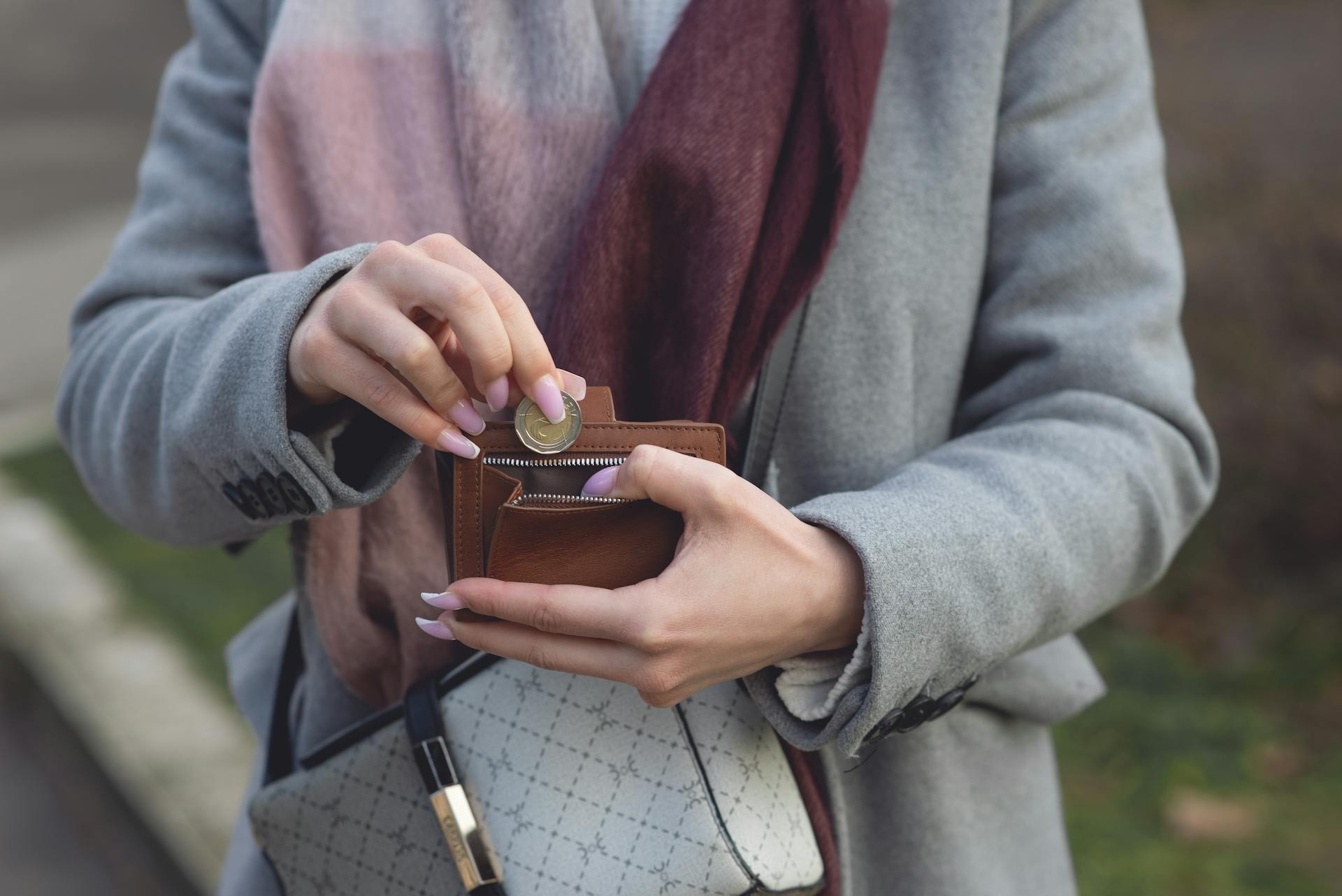 Close-Up Shot of a Person Putting a Coin in a Wallet